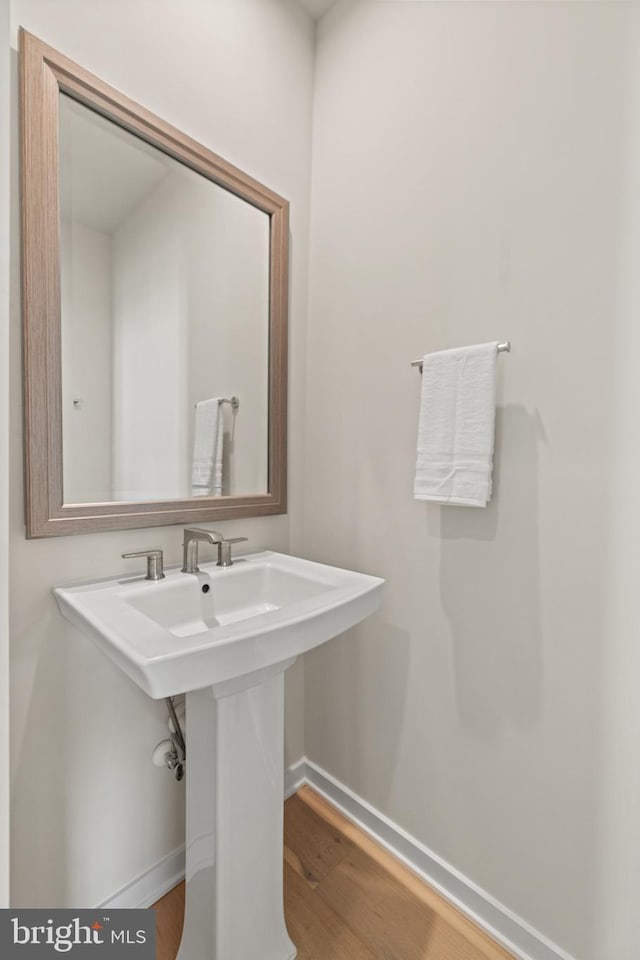 bathroom featuring wood finished floors, baseboards, and a sink