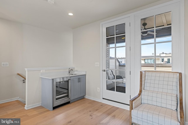 sitting room with beverage cooler, recessed lighting, light wood finished floors, and baseboards