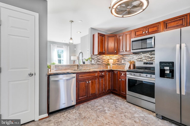 kitchen with light stone counters, a sink, appliances with stainless steel finishes, pendant lighting, and backsplash