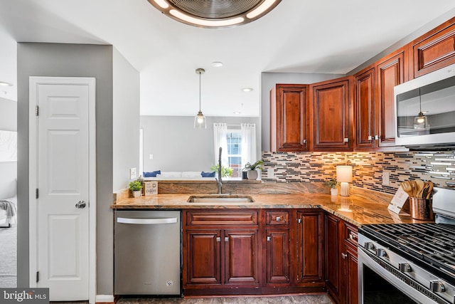 kitchen featuring light stone countertops, pendant lighting, decorative backsplash, appliances with stainless steel finishes, and a sink