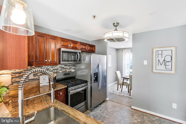 kitchen with baseboards, light stone counters, decorative backsplash, stainless steel appliances, and a sink