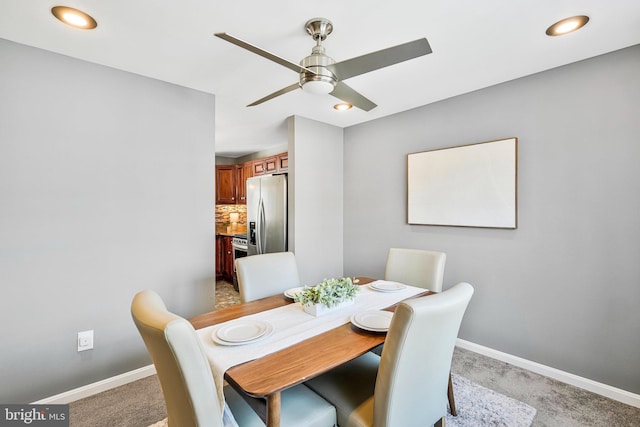 dining room with a ceiling fan, baseboards, and light carpet