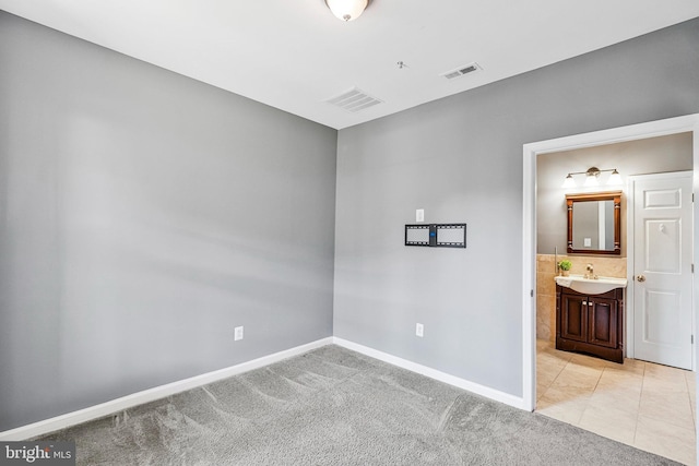 unfurnished room with light carpet, visible vents, and a sink