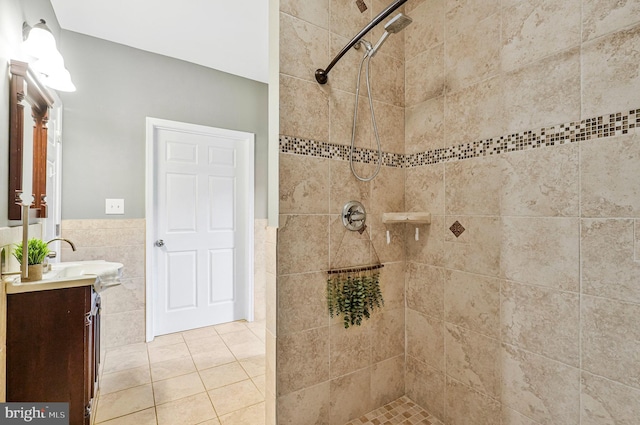 full bathroom with vanity, a wainscoted wall, tiled shower, tile walls, and tile patterned floors