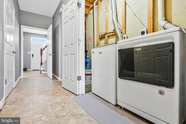 clothes washing area featuring baseboards, washer / clothes dryer, and laundry area