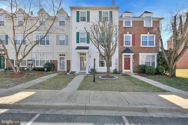 view of property with brick siding and a front lawn