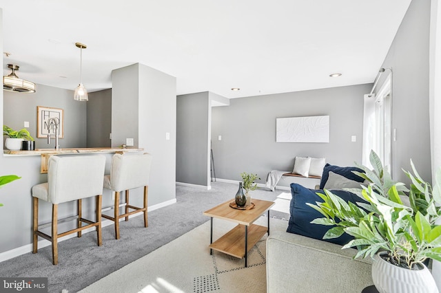 carpeted living area featuring baseboards and a sink