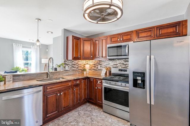 kitchen featuring tasteful backsplash, light stone counters, hanging light fixtures, stainless steel appliances, and a sink