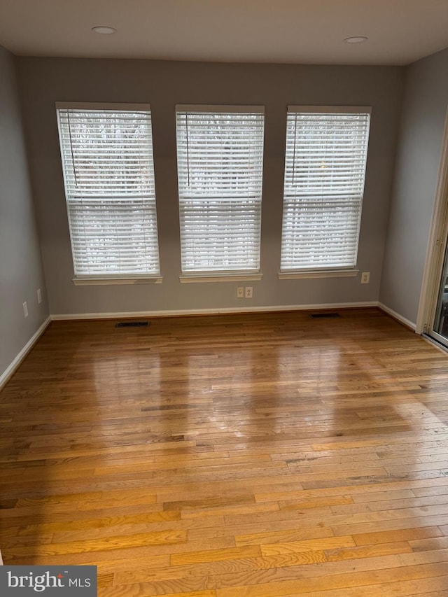 unfurnished room with light wood-type flooring, baseboards, visible vents, and a healthy amount of sunlight