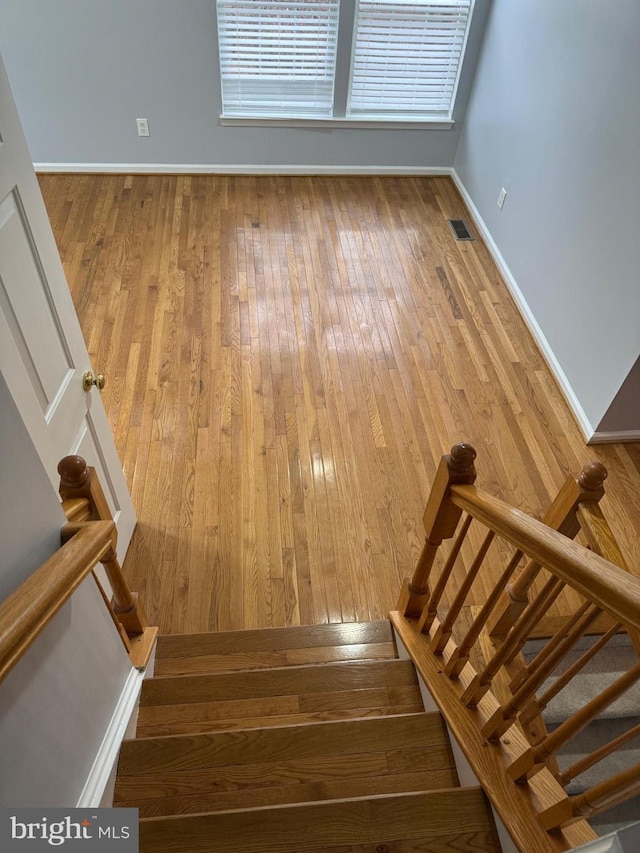 stairway featuring visible vents, baseboards, and wood-type flooring