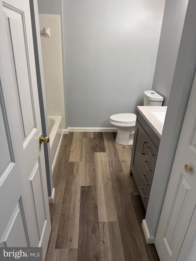 full bathroom with toilet, vanity, baseboards, and wood finished floors