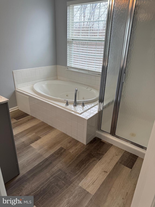 bathroom featuring wood finished floors, a stall shower, and a whirlpool tub