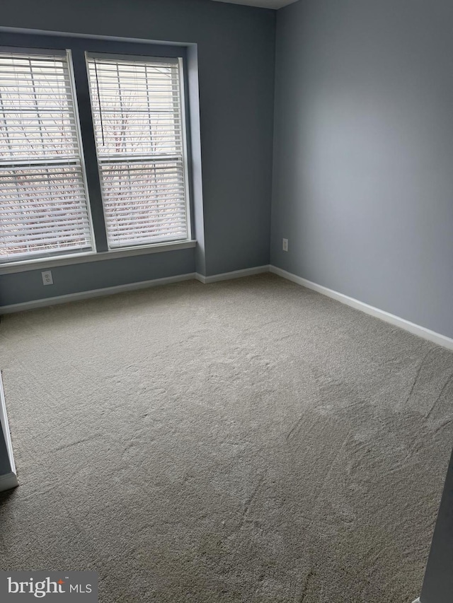 carpeted spare room featuring baseboards