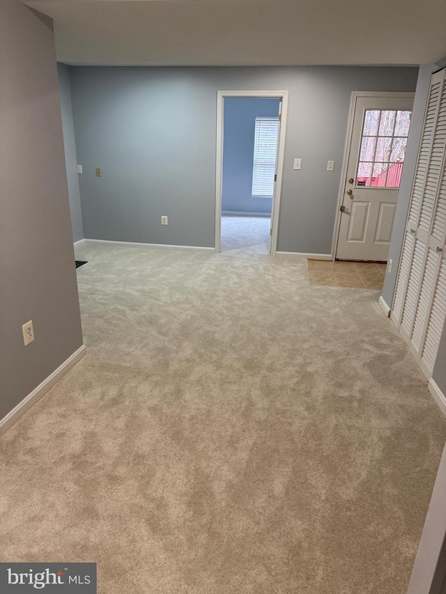 interior space with baseboards and light carpet