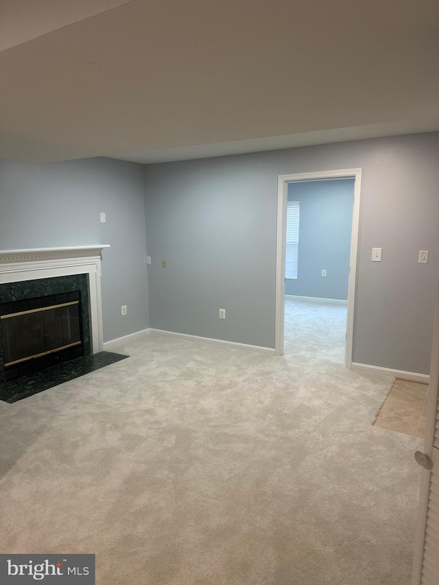 unfurnished living room with a high end fireplace, baseboards, and carpet floors