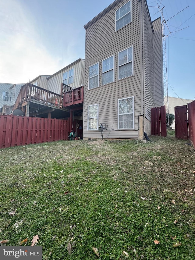 rear view of property featuring a lawn and fence