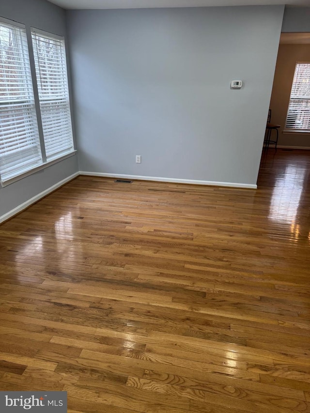 unfurnished room with visible vents, wood finished floors, and baseboards