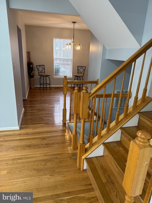 stairs with a chandelier, baseboards, and wood finished floors