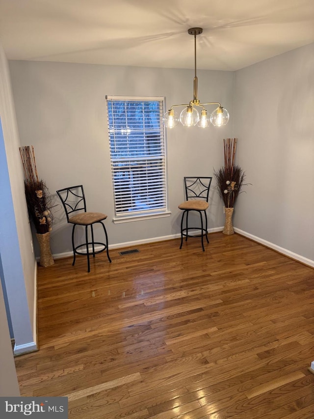 unfurnished room featuring a notable chandelier, visible vents, baseboards, and wood finished floors