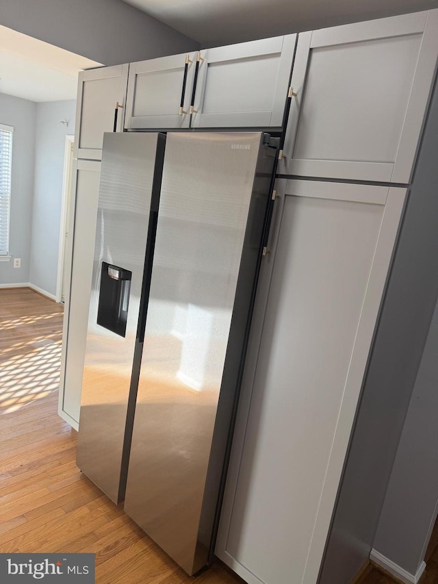 kitchen featuring baseboards, stainless steel fridge, and light wood finished floors