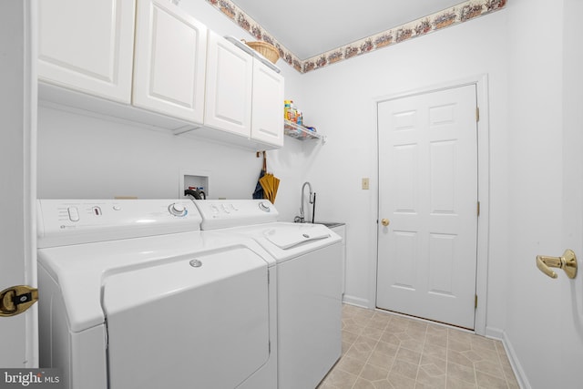 washroom featuring cabinet space, baseboards, and washing machine and clothes dryer