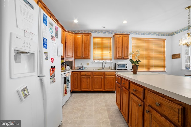 kitchen with white appliances, light countertops, brown cabinets, and a sink