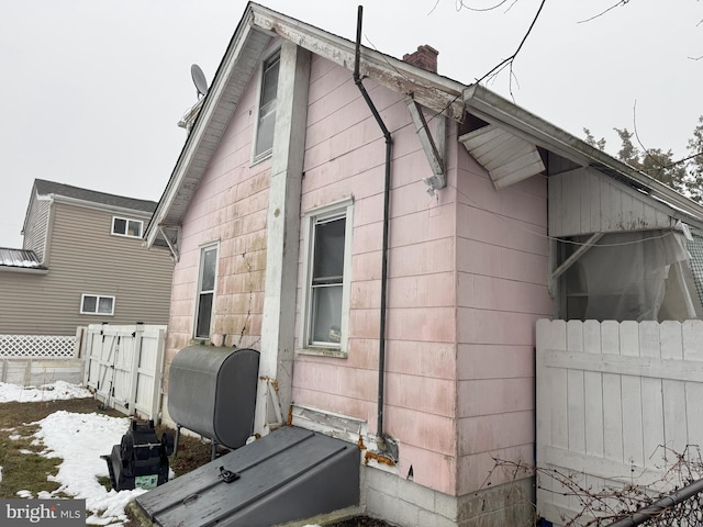 view of side of property featuring a chimney, heating fuel, and fence