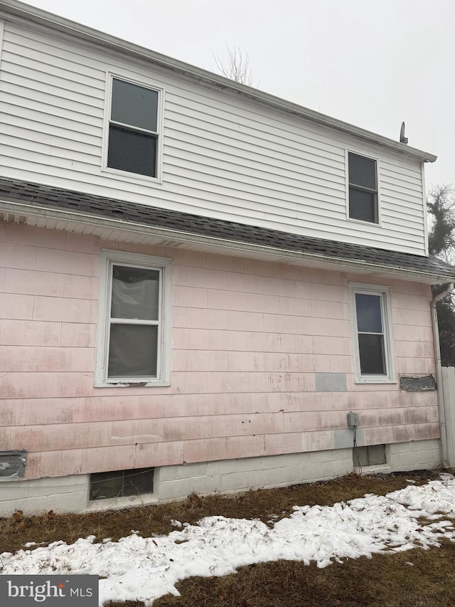 view of side of home with roof with shingles