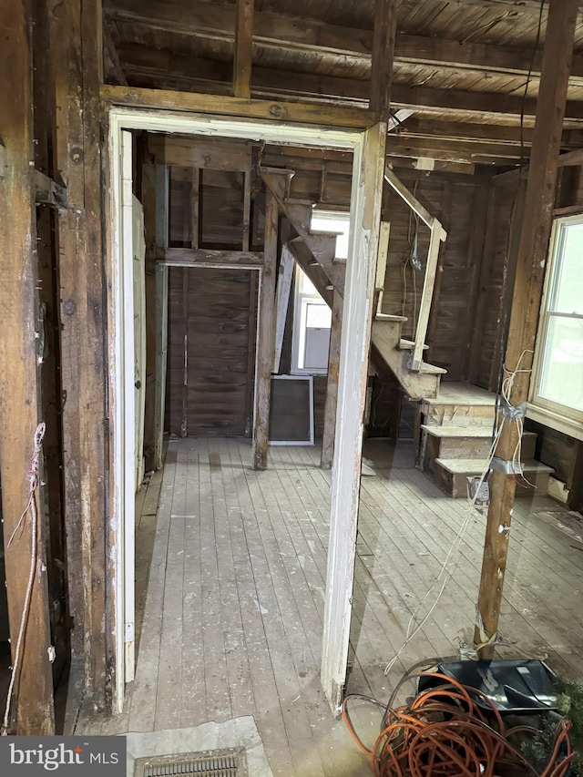 misc room featuring stairway, beamed ceiling, and hardwood / wood-style floors