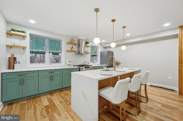 kitchen with open shelves, stainless steel appliances, wall chimney exhaust hood, light wood finished floors, and green cabinetry