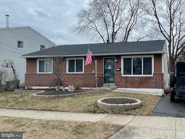 view of front of property featuring brick siding and roof with shingles