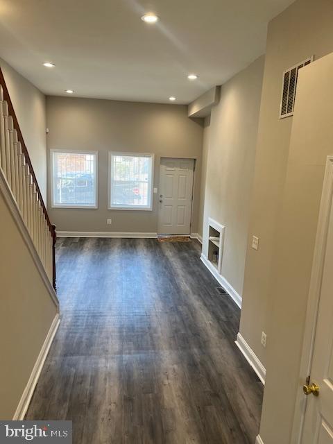 unfurnished living room with dark wood-style floors, visible vents, and baseboards