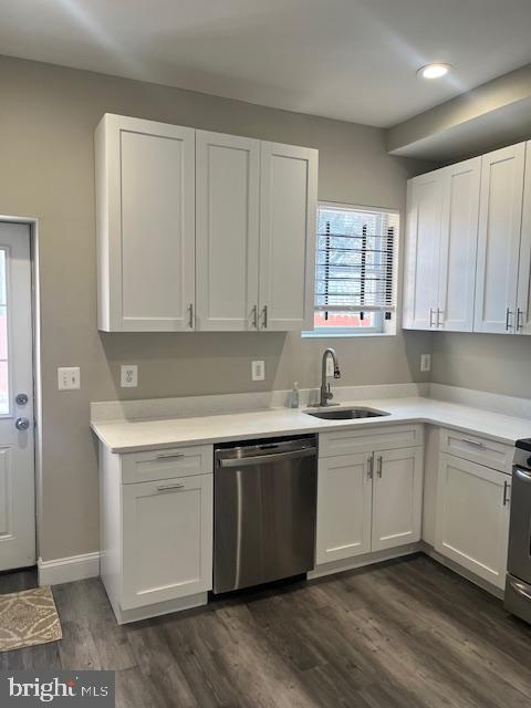 kitchen featuring dark wood-type flooring, dishwasher, light countertops, white cabinets, and a sink