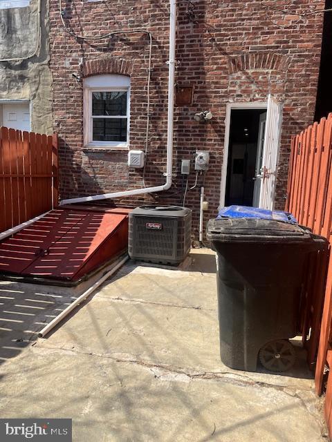 exterior space with brick siding, central AC unit, and fence