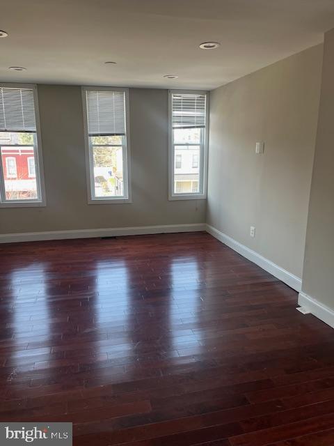 spare room featuring a wealth of natural light, baseboards, and wood finished floors