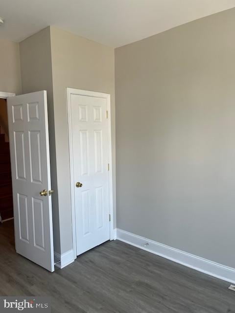 unfurnished bedroom featuring baseboards and dark wood-style flooring