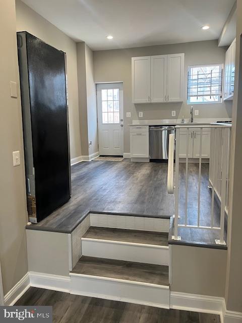 kitchen featuring baseboards, dark wood finished floors, dishwasher, recessed lighting, and white cabinetry