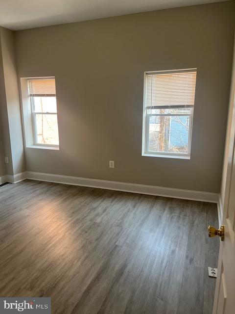 spare room featuring dark wood-style floors and baseboards