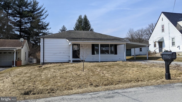 ranch-style home featuring a carport, driveway, a front yard, and roof with shingles