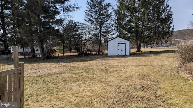 view of yard featuring an outbuilding, fence, and a shed