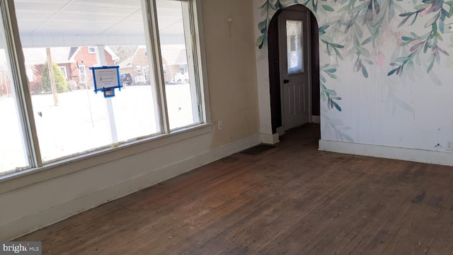 spare room featuring visible vents, baseboards, and wood finished floors