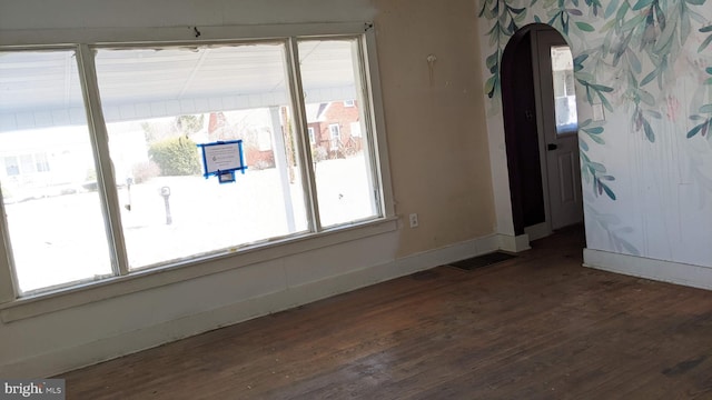 spare room featuring wood finished floors, visible vents, and baseboards