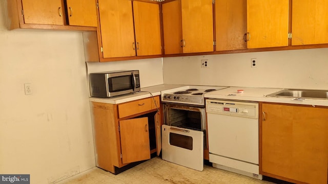 kitchen with light floors, white appliances, light countertops, and a sink