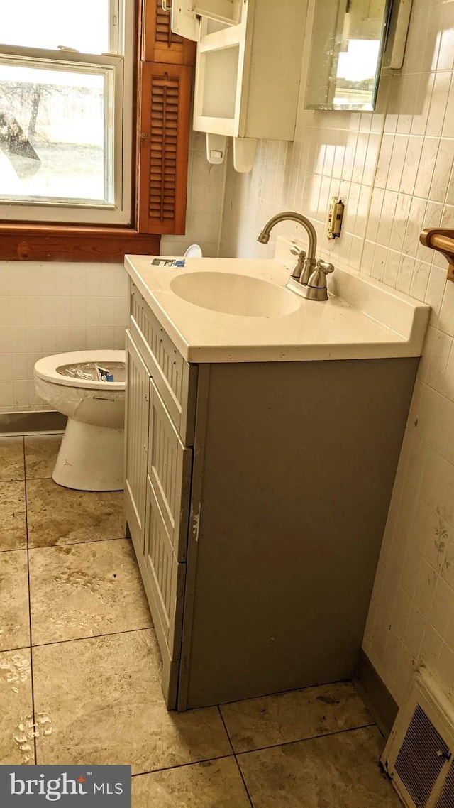 half bath featuring vanity, tile walls, toilet, and tile patterned floors