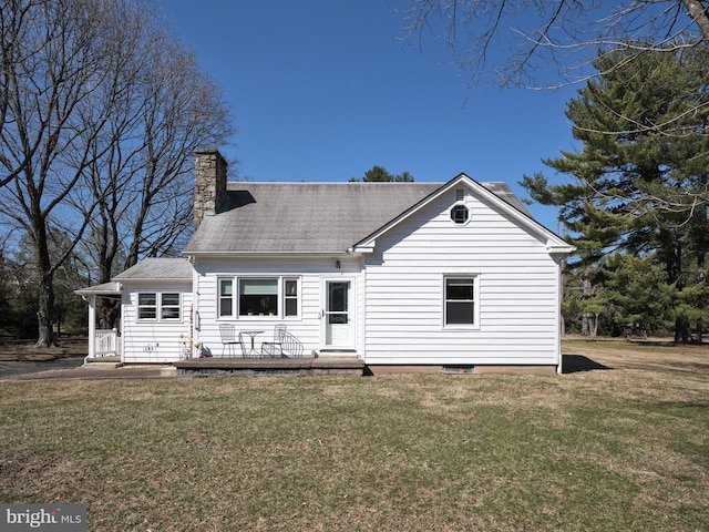 rear view of property with a wooden deck, a yard, and a chimney