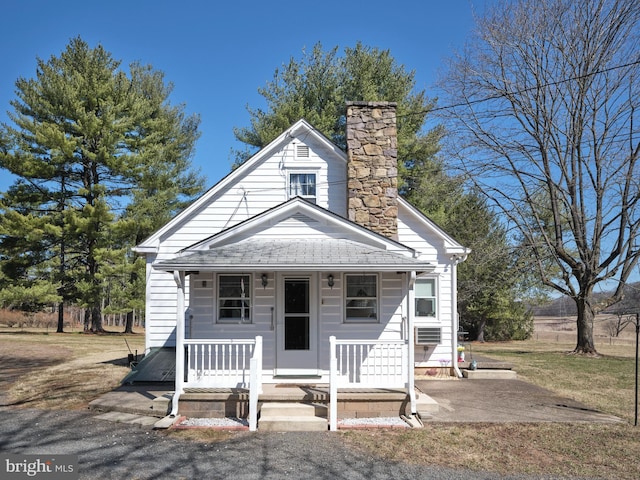 view of front of property featuring cooling unit, covered porch, and a chimney