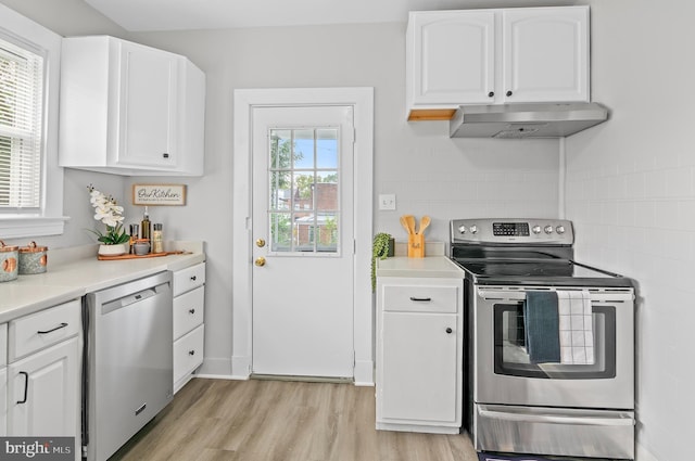 kitchen featuring light wood-type flooring, appliances with stainless steel finishes, exhaust hood, and white cabinetry