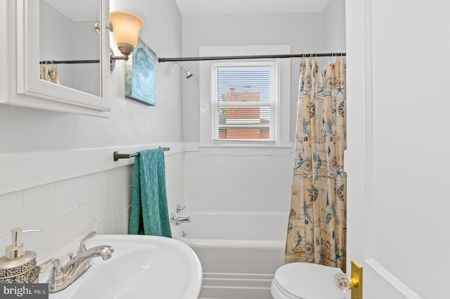 full bath featuring a sink, toilet, tile walls, and shower / tub combo with curtain