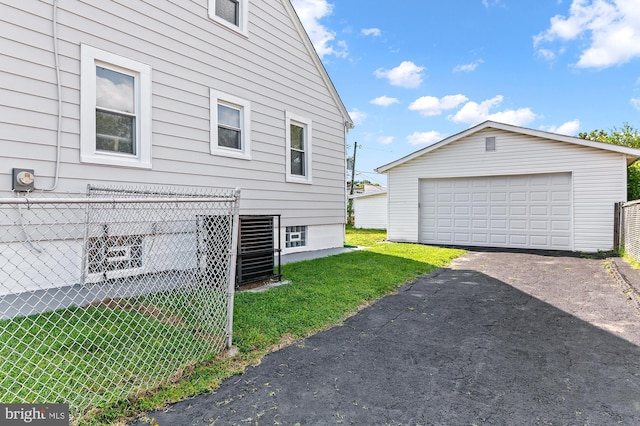 view of side of property featuring a yard, a detached garage, an outdoor structure, and fence