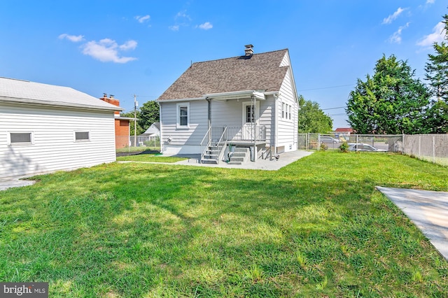 back of property with a yard, a shingled roof, and fence